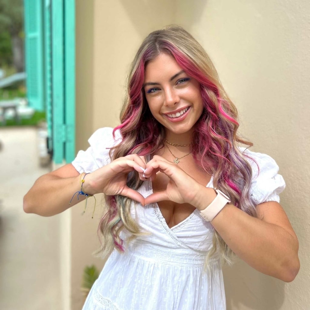 Influencerin Chany Dakota formt mit ihren Händen ein Herz und setzt damit ein Zeichen im Kampf gegen Brustkrebs.