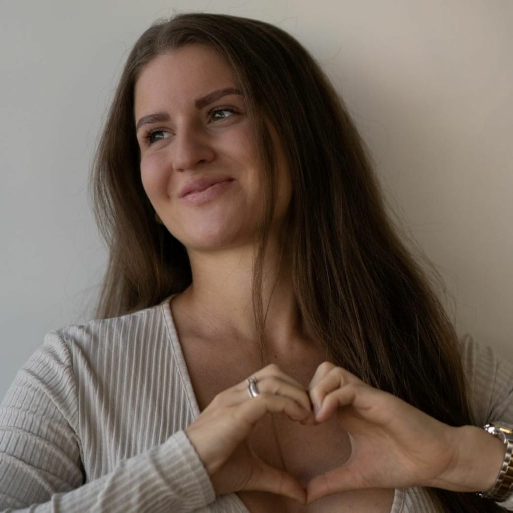 Influencerin Romina Campion formt mit ihren Händen ein Herz und setzt so ein Zeichen im Kampf gegen Brustkrebs.