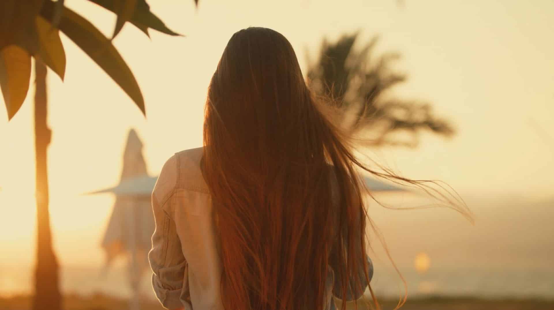 Eine Frau mit langen dunkelbraunen Haaren sieht in die Ferne.