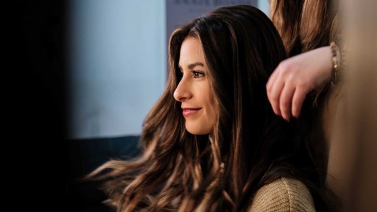 Woman with long hair in balayage look smiles in the mirror