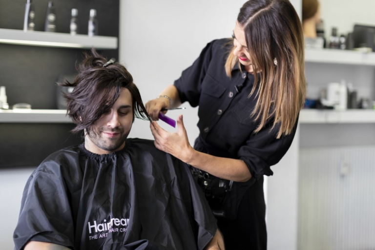 Une coiffeuse Hairdreams coupe les cheveux d'un homme après un épaississement de la chevelure par folium.