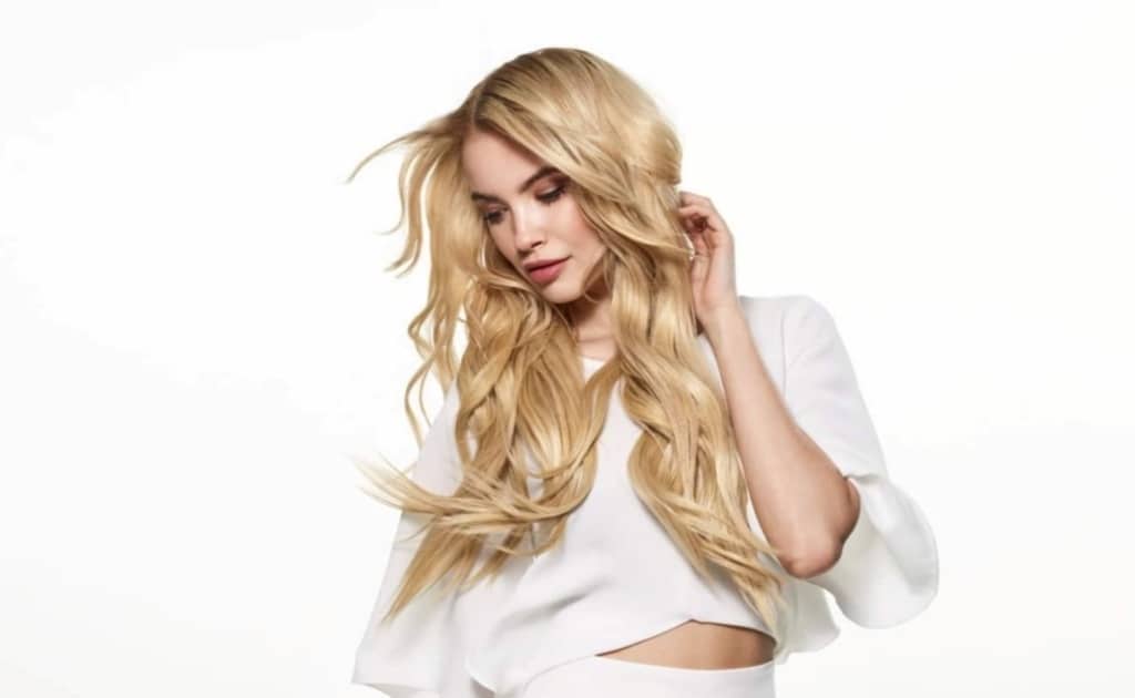 Femme portant des extensions à bande adhésive longues et blondes Hairdreams